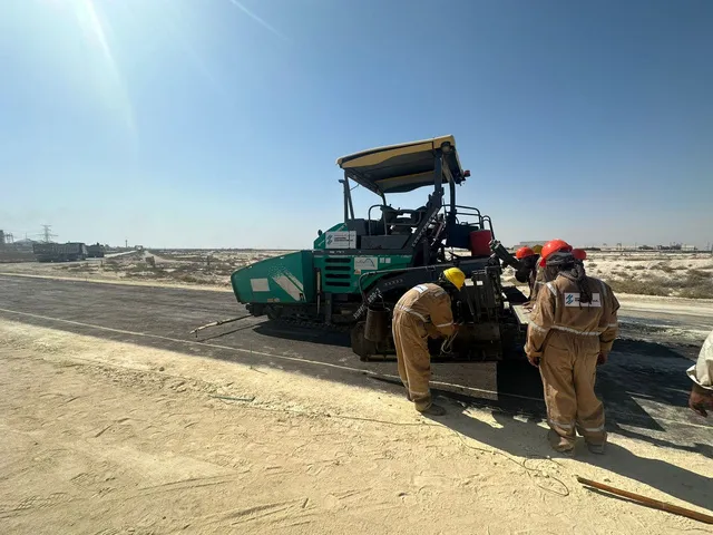 Asphalt paver and crew laying a new road