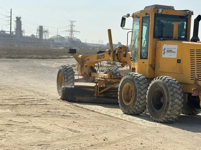Motor grader working with gas plant in the background