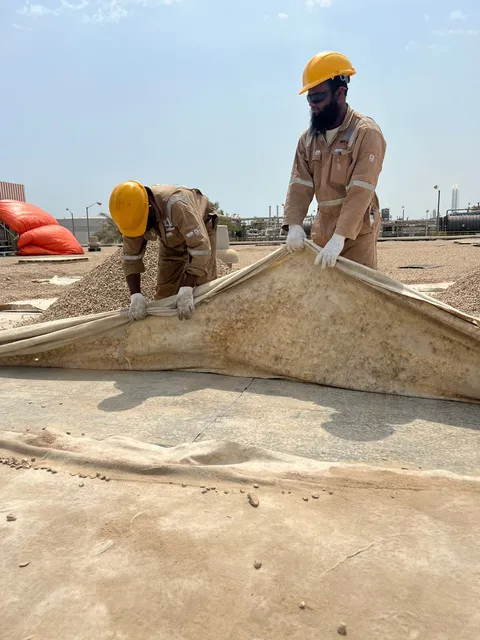 Crew installing waterproofing membrane layers on a roof